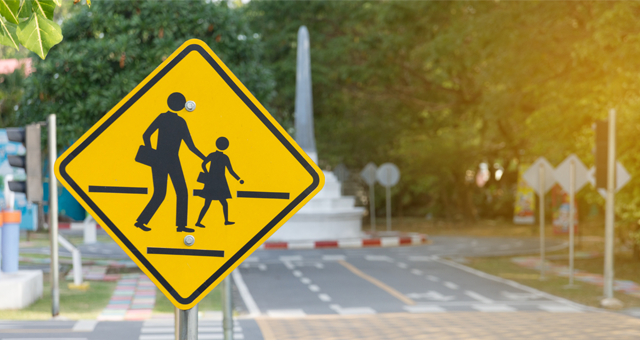 A road sign of two people crossing in a crosswalk