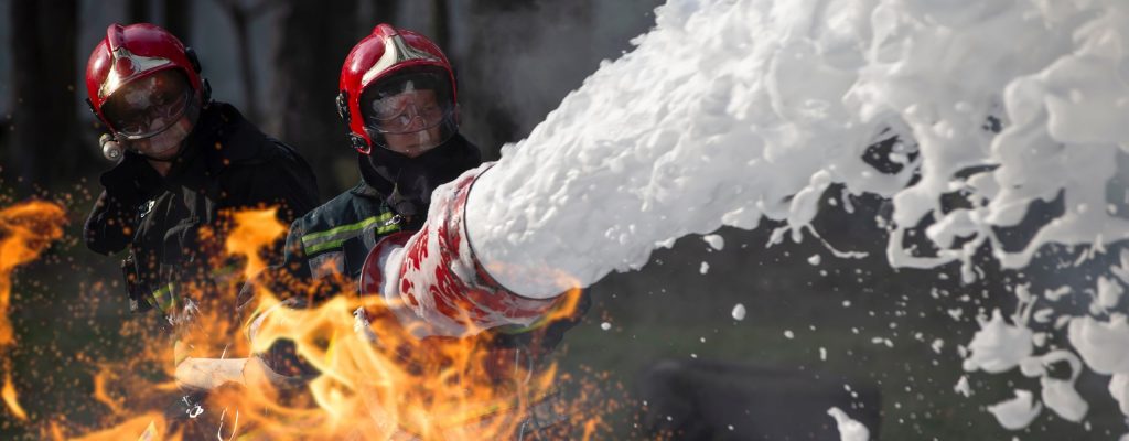 Firefighters extinguish a fire. Lifeguards with fire hoses in smoke and fire.